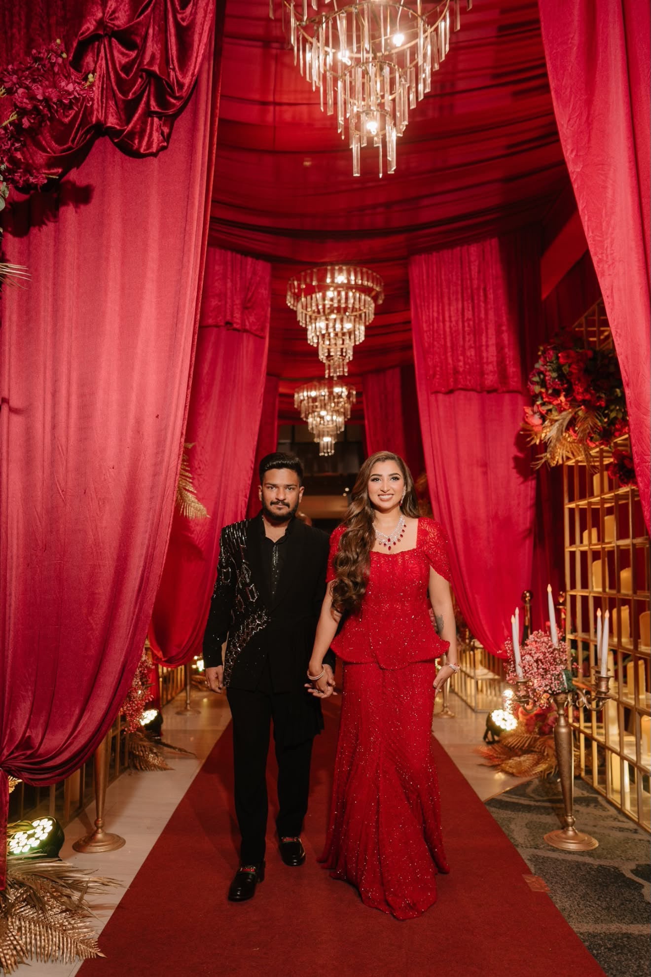A K&A client walking a candlelit aisle in a hand-embellished maroon gown
