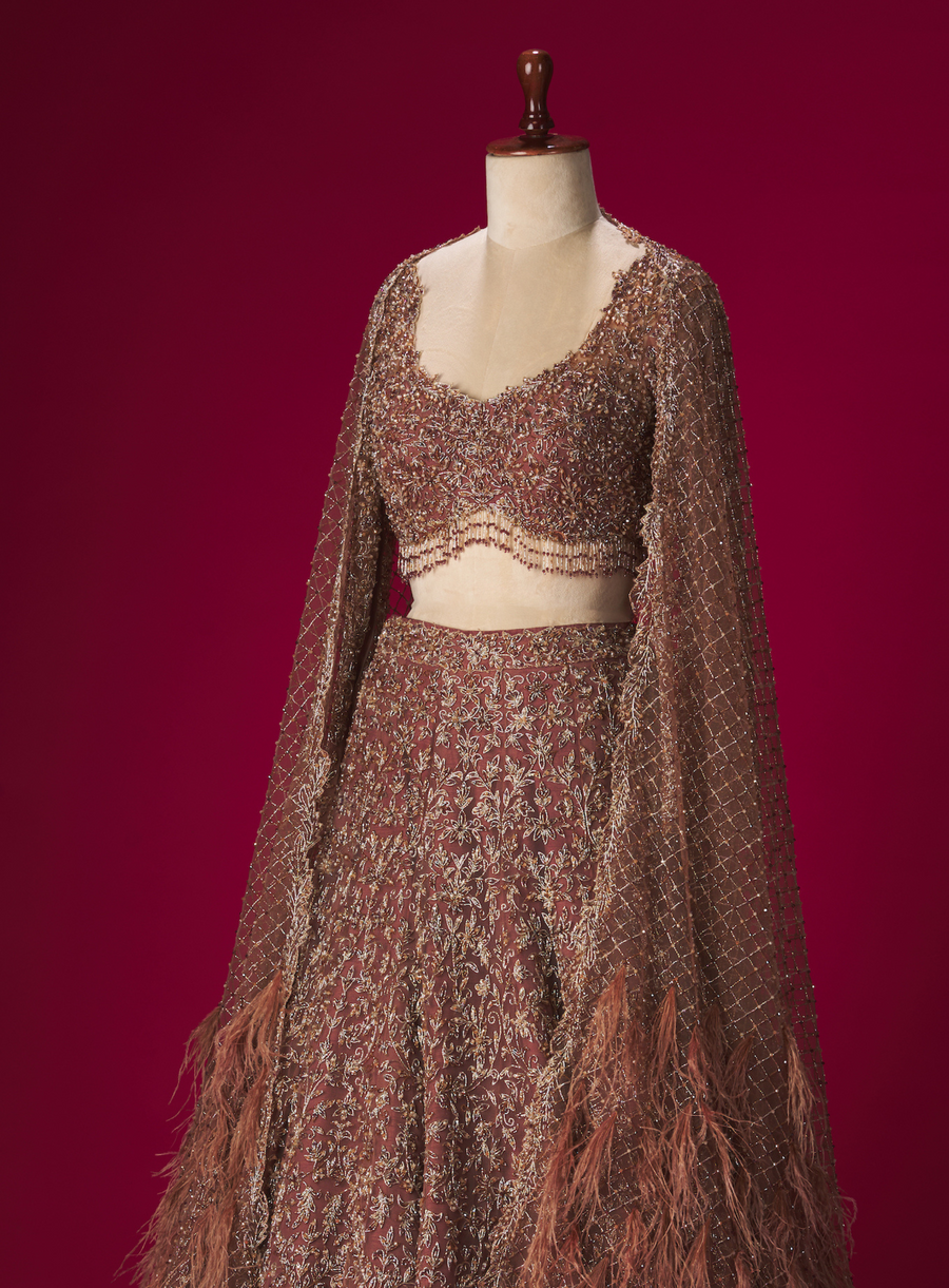 Side view of the brown embellished lehenga with beaded blouse and feather-trimmed dupatta on a mannequin