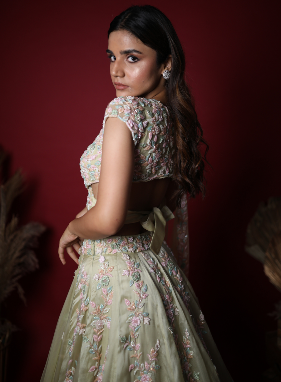 Back view of the sage green lehenga blouse with floral embroidery and bow tie-back