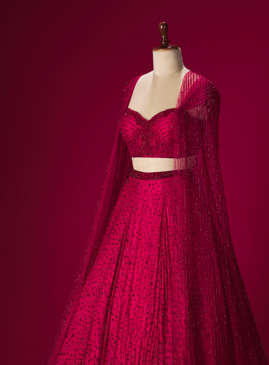 Side view of the red crystal lehenga with corset and sheer embellished cape on a mannequin
