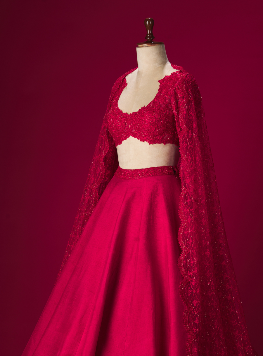 Side view of the cherry red cut-work blouse with lehenga and embellished dupatta on a mannequin