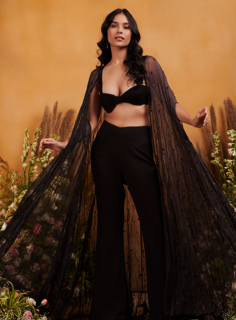 Black pleated bustier with flared pants and hand-embellished cape