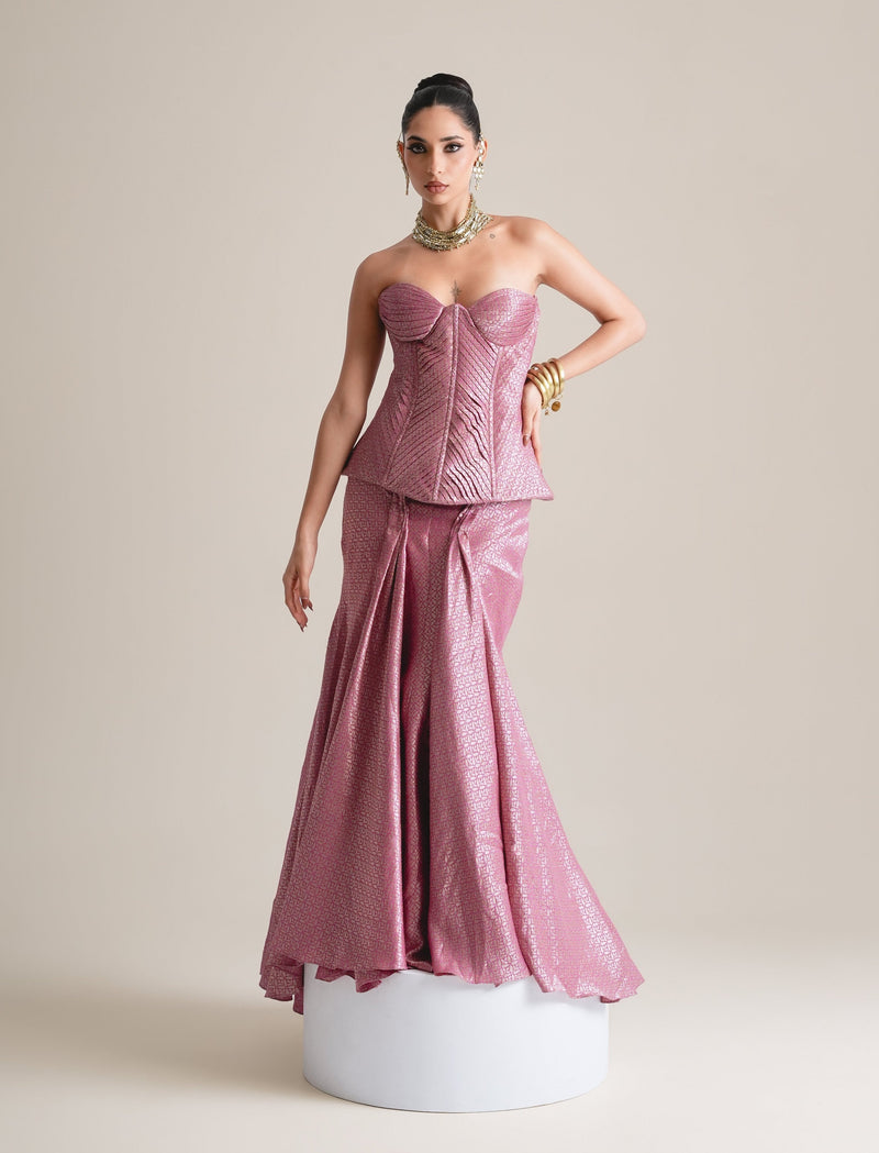 Rose-pink metallic quilted sweetheart corset with pointed peplum and fishcut skirt in hand-woven Banarasi brocade, full-length front view standing on a white plinth