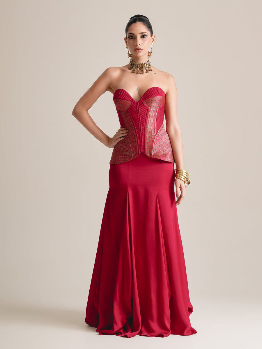 Crimson red strapless sweetheart corset with rose-pink panelled peplum sides and a flared fishcut skirt, full-length front view, hands on hips