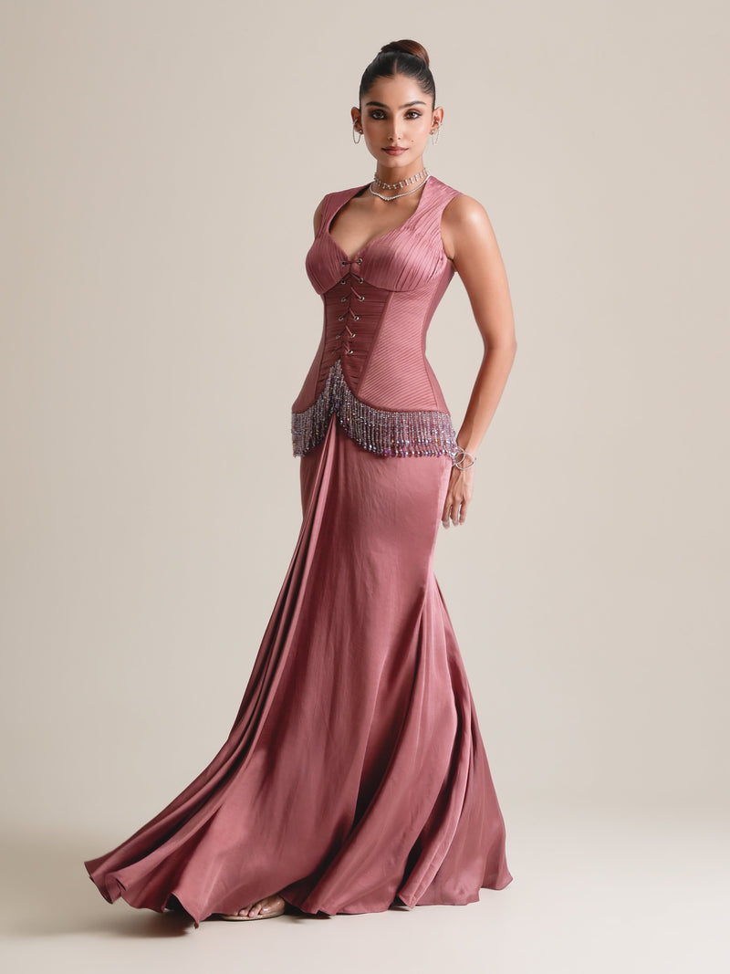 Dusty-rose lace-up corset with wide straps, beaded fringe at the hip and a flowing fishcut skirt, full-length front view in movement