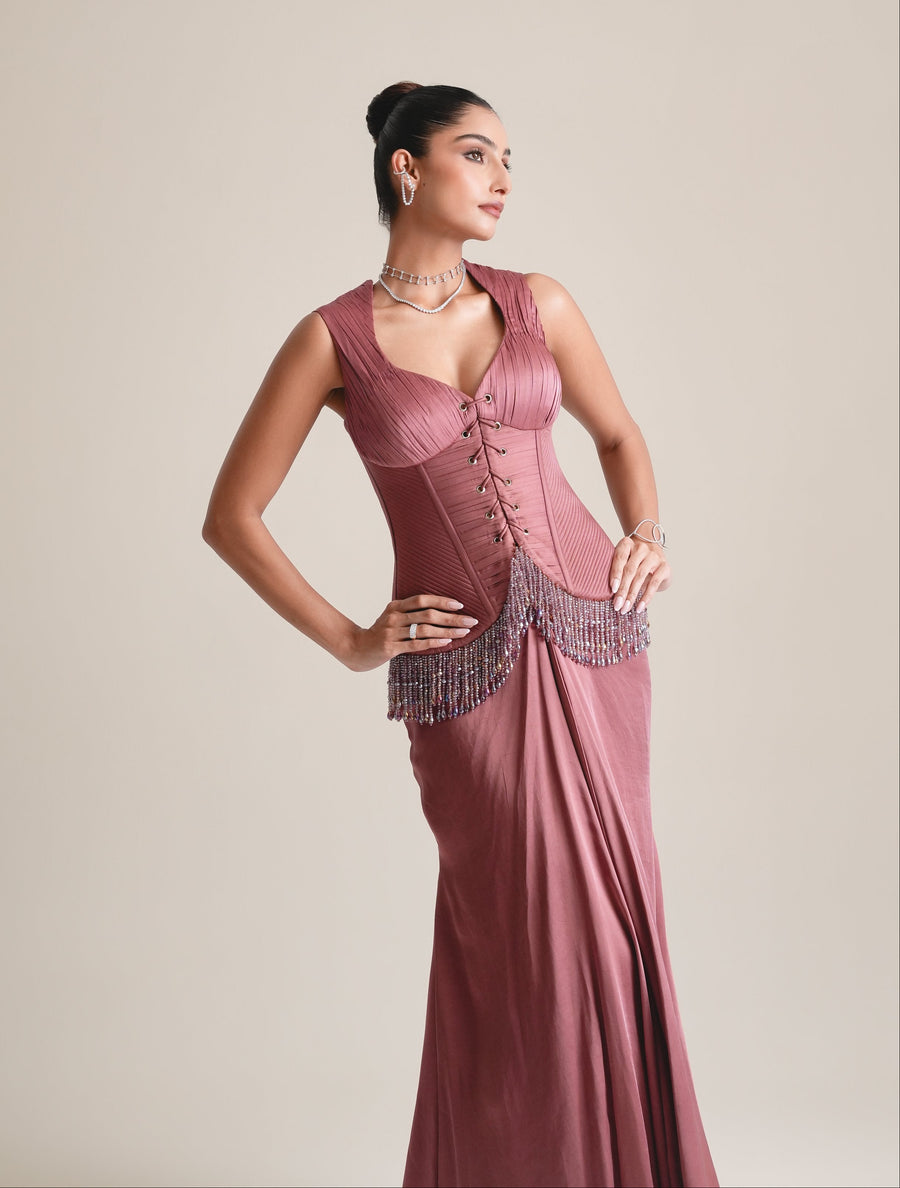 Three-quarter view of the dusty-rose lace-up corset with beaded fringe at the hip, hands on hips