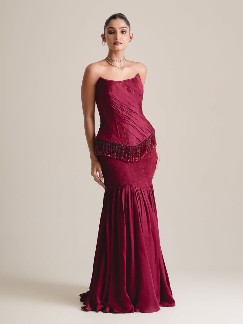 Wine-red strapless corset with a beaded fringe at the hip and a fitted skirt flaring into a full hem, full-length front view