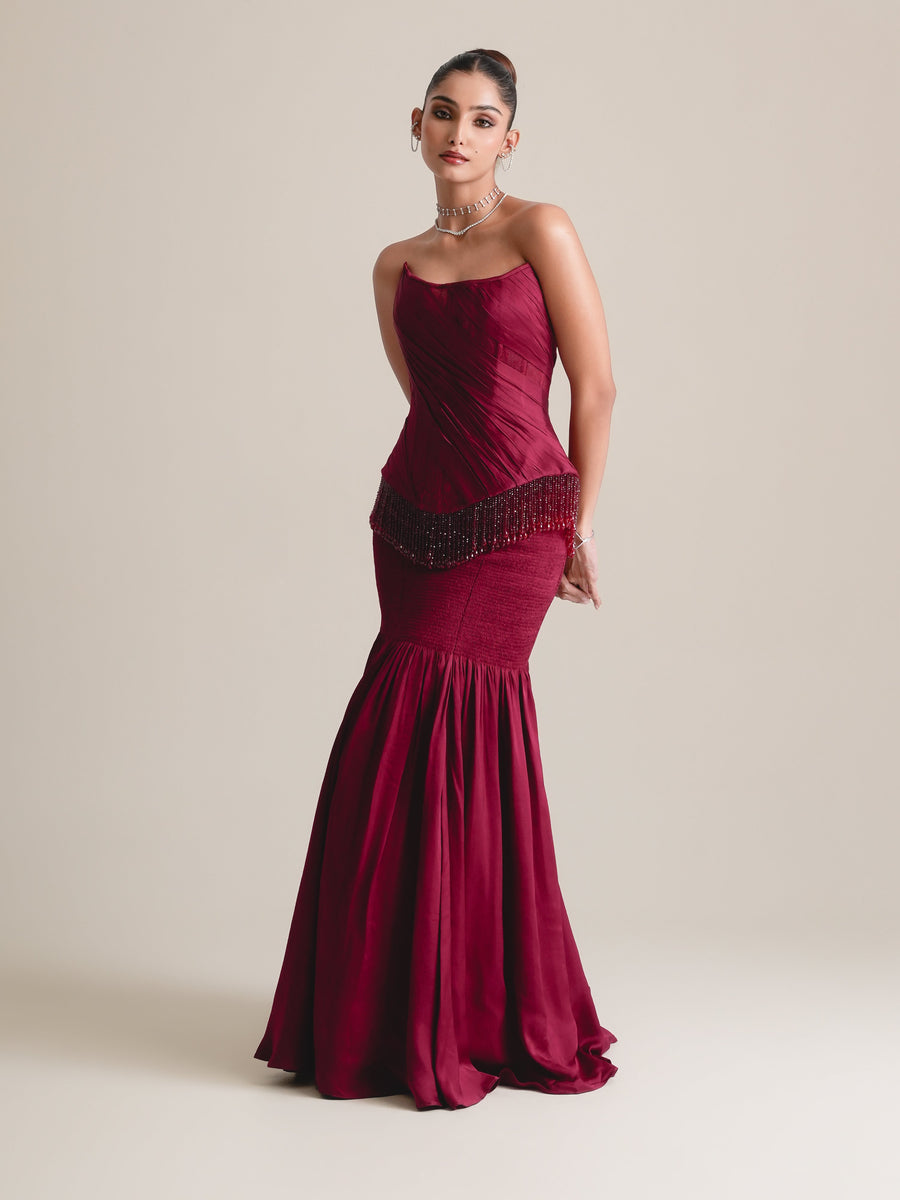 Wine-red strapless corset with beaded fringe and a fitted, gathered skirt flaring at the hem, full-length view