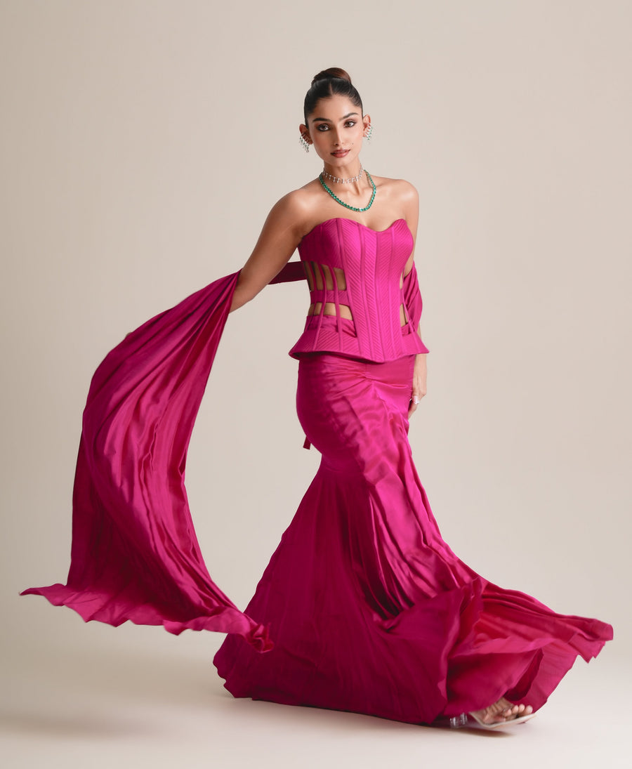 Hot-pink cage corset and fishcut drape skirt with the stole swept out behind, full-length view in movement