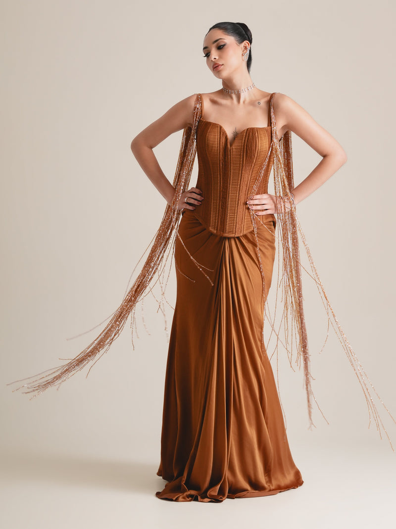 Rust-copper pleated corset with long beaded tassel fringe falling from the straps and a draped skirt, full-length front view, hands on hips