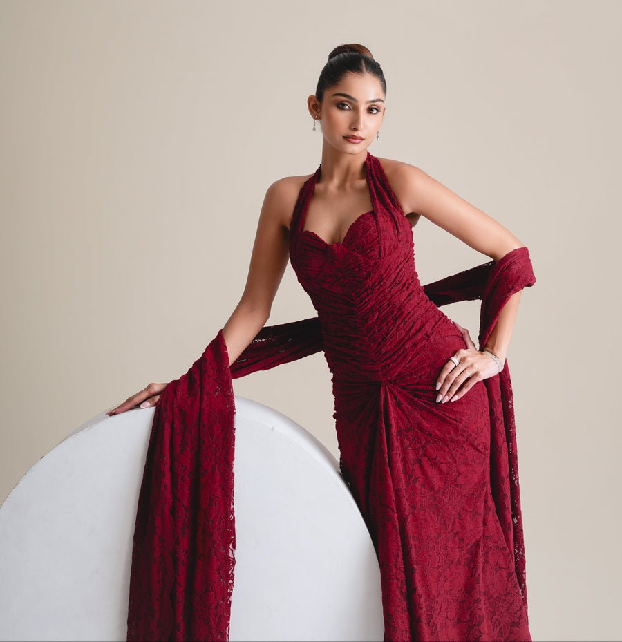 Three-quarter view of the maroon lace halter corset with ruched bodice and stole, leaning on a white plinth