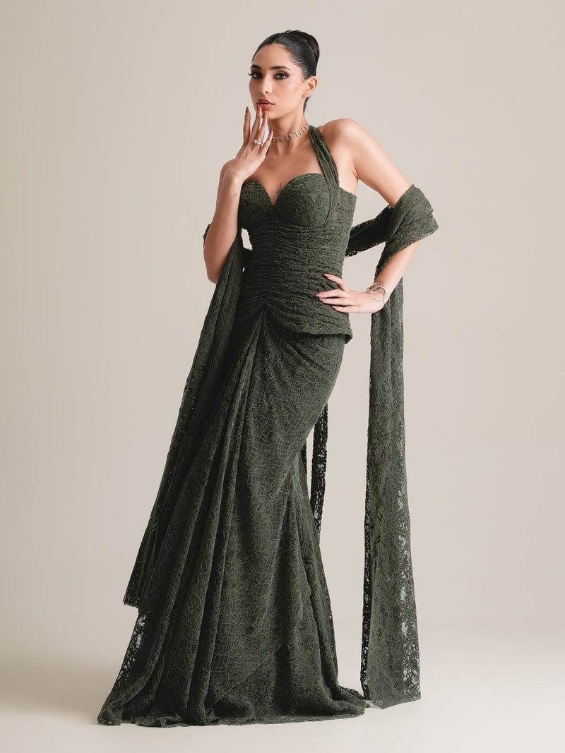 Olive-green lace halter corset with ruched bodice, a long lace stole and a draped fishcut skirt, full-length view, fingertips to the lips