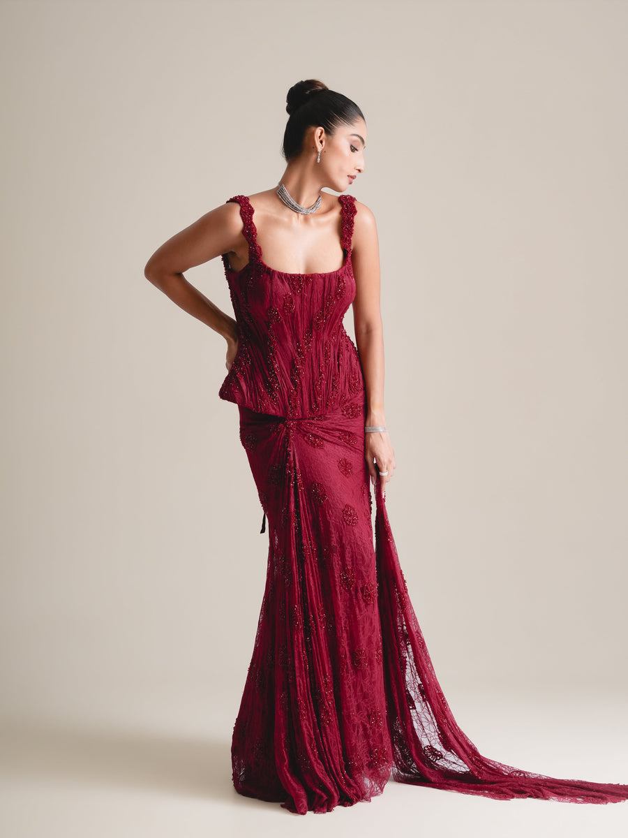 Maroon square-neck embroidered corset and fishcut skirt with a long lace train trailing to one side, full-length view