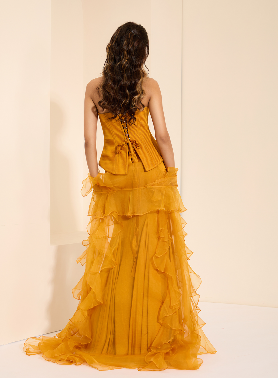 Back view of the mustard lace-up corset with ruffled organza cape trailing behind