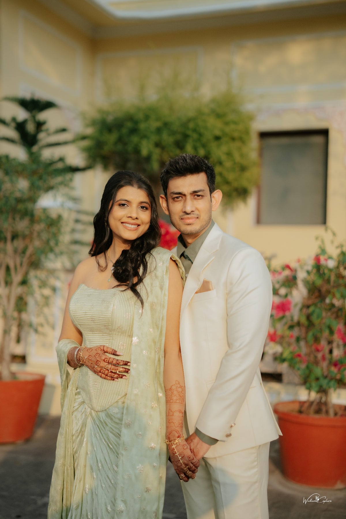 Jinali Shah in a sage green jacquard corset with drape skirt, couple portrait at a palace courtyard
