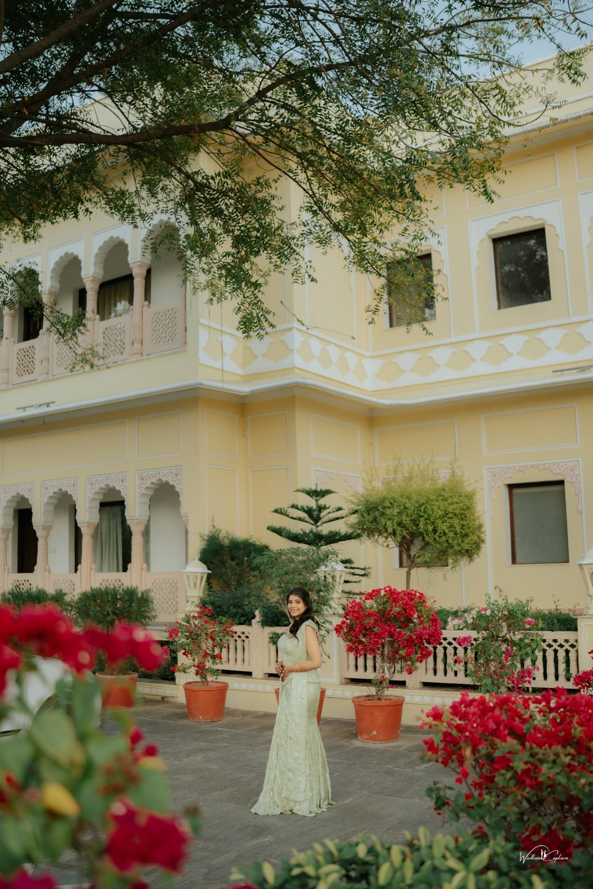 Jinali Shah in a sage green jacquard corset with drape skirt, candid full-length moment in a palace garden