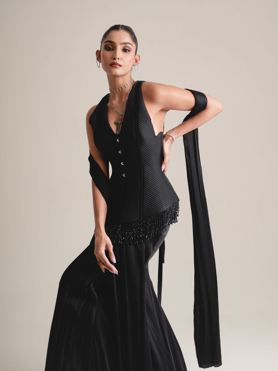 Three-quarter view of the black V-neck quilted corset with beaded fringe, hand on hip and stole draped over the arm