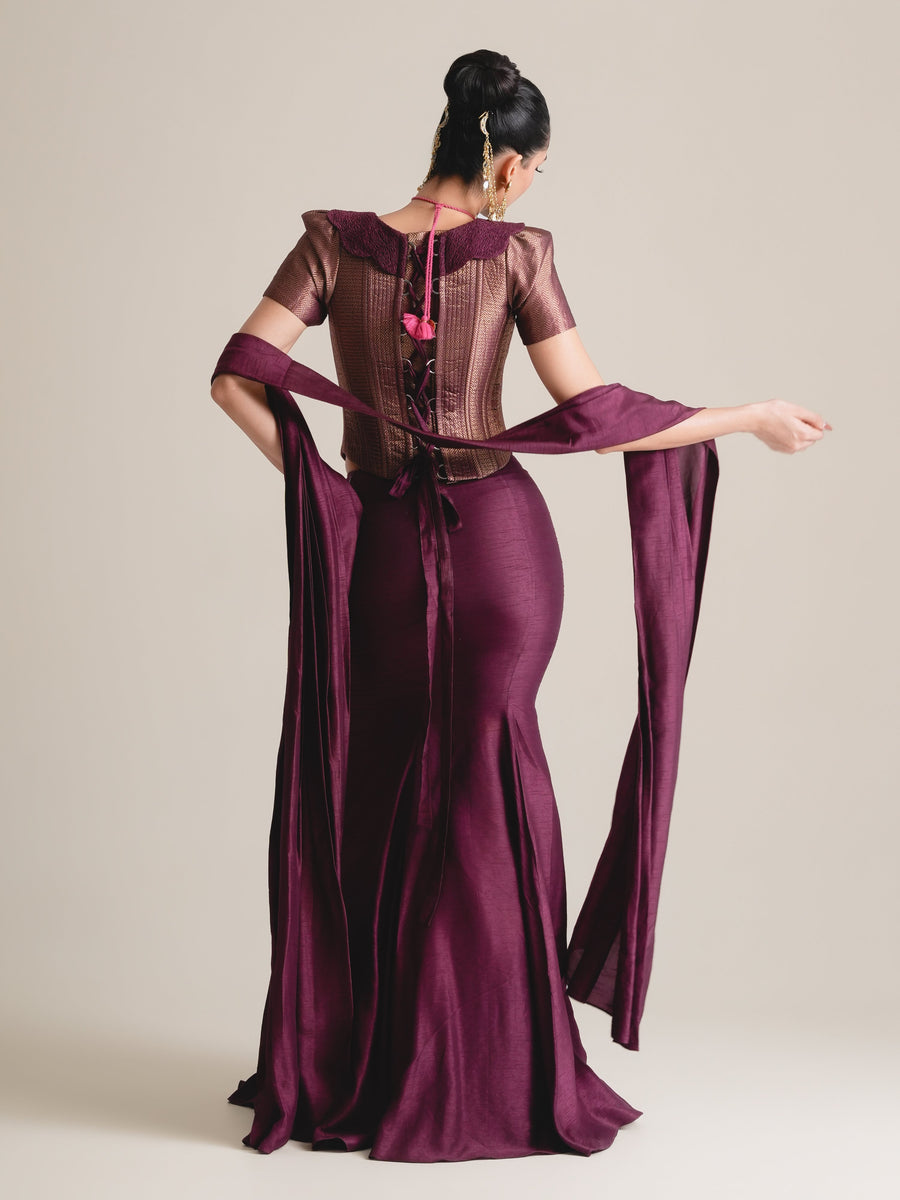 Back view of the plum puff-sleeve corset with lace-up back, stole across the arms and drape skirt, full length