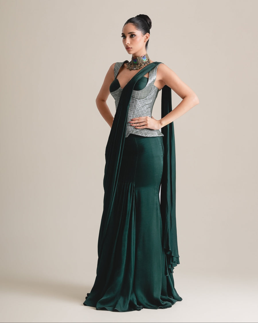 Silver-grey brocade corset with emerald cups and a bottle-green drape saree, full-length three-quarter view, hands on hips