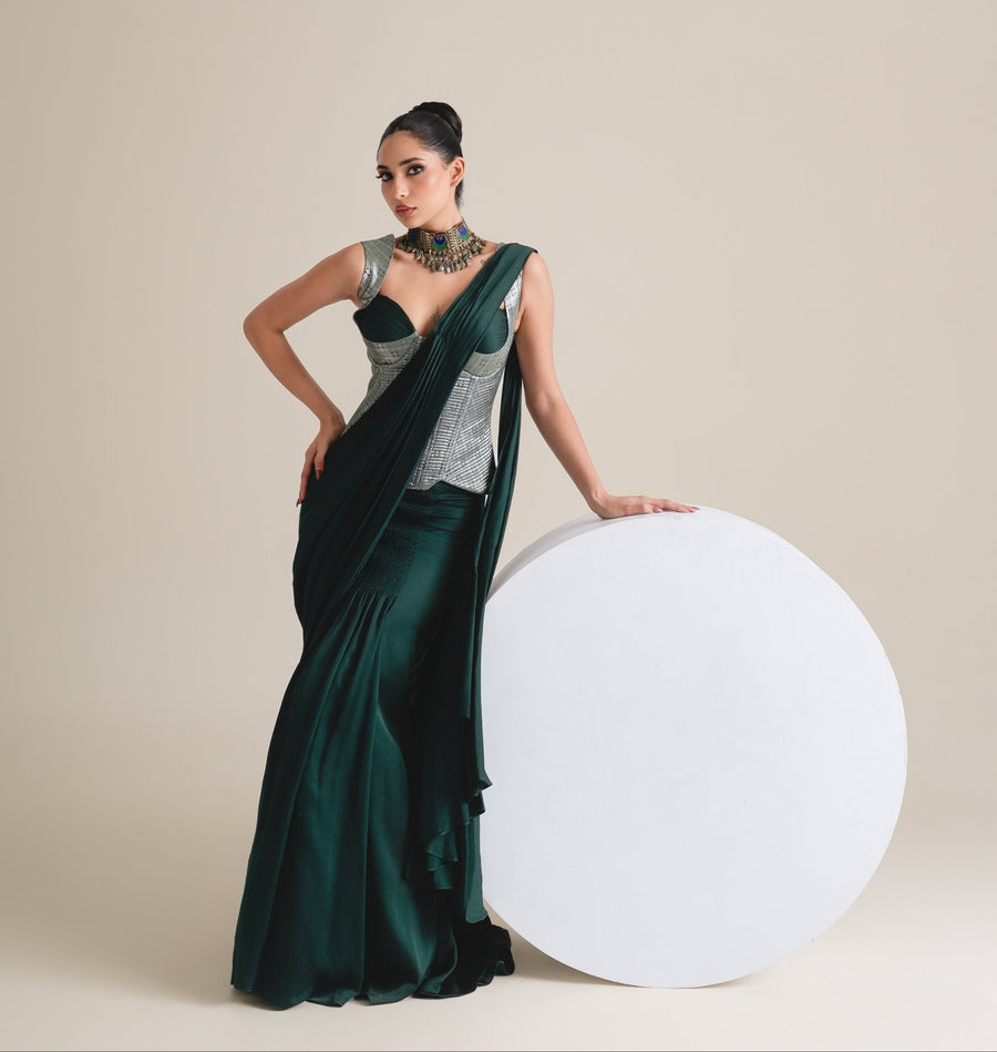 Silver-grey corset and bottle-green drape saree, full-length view standing beside a white disc