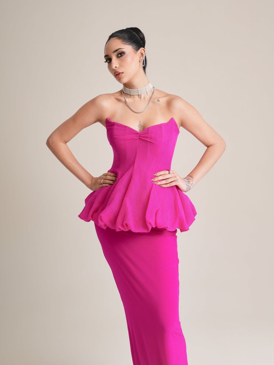Three-quarter view of the fuchsia strapless corset with bubble peplum, hands on hips