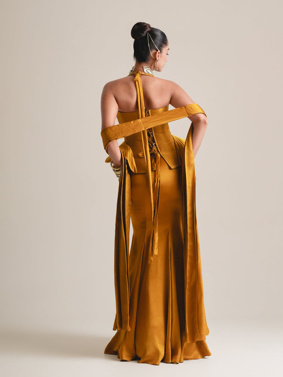 Back view of the mustard halter corset with lace-up back, stole across the arms and fishcut skirt, full length