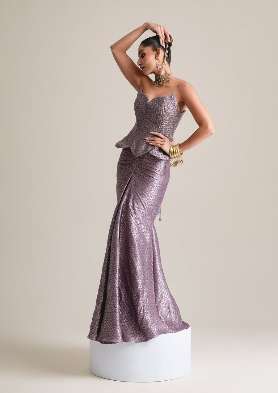 Lilac-grey scalloped corset and ruched fishcut skirt, full-length view with one arm raised, standing on a white plinth