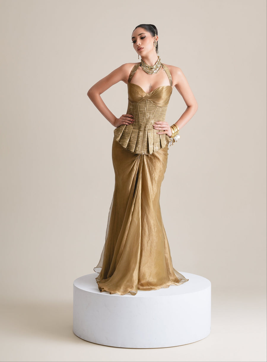 Antique-gold halter corset with box-pleated peplum and sheer tissue skirt, full-length front view on a white plinth
