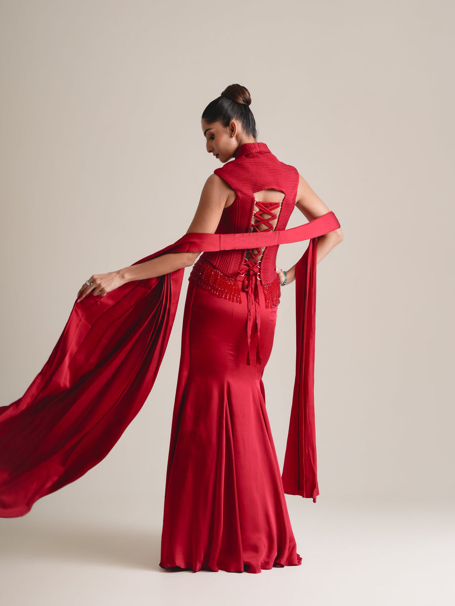 Back view of the red corset with cut-out lace-up back, stole sweeping out and fishcut drape skirt, full length