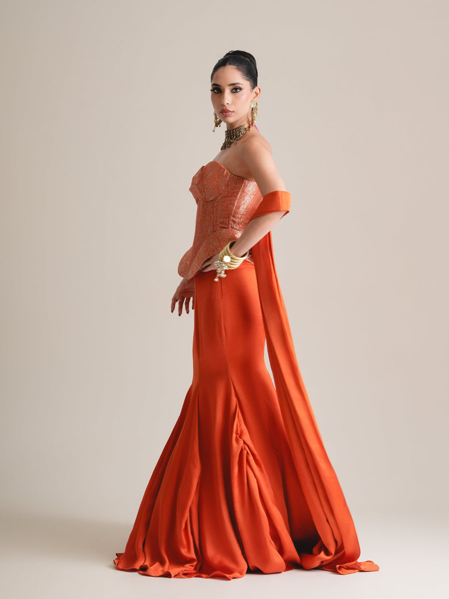 Copper-orange brocade corset with peplum and fishcut skirt, stole falling from the arm, full-length three-quarter view