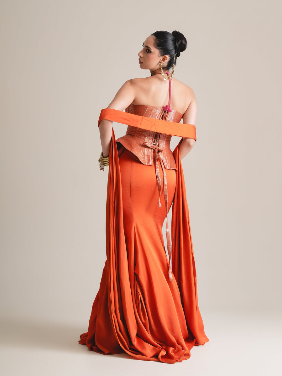 Back view of the copper-orange brocade corset with lace-up back, stole across the arms and fishcut skirt, full length
